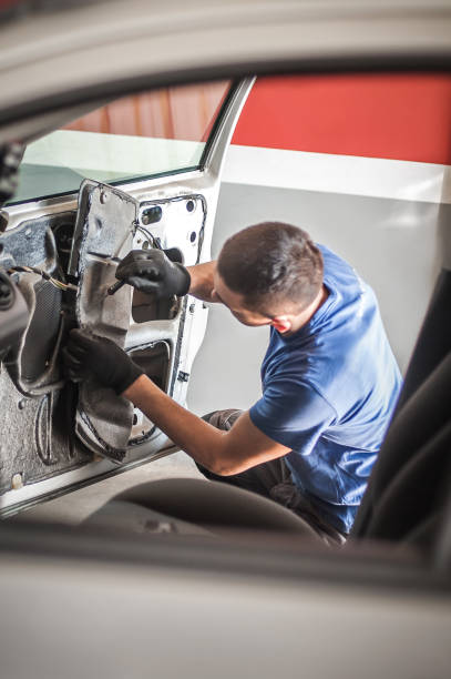 Car master mechanic works on the interior of a car door at vehicle service workshop